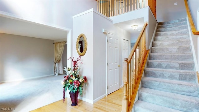 stairs with hardwood / wood-style flooring and a high ceiling