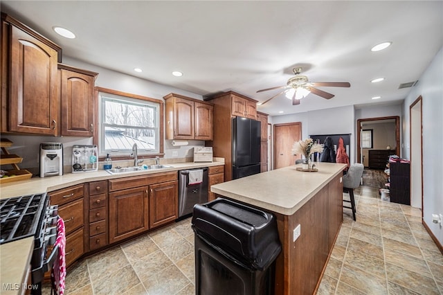 kitchen with a breakfast bar, sink, black refrigerator, dishwasher, and gas range oven