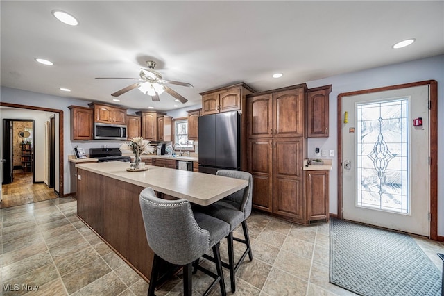 kitchen featuring sink, ceiling fan, appliances with stainless steel finishes, a kitchen breakfast bar, and a kitchen island