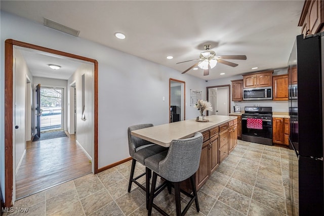 kitchen featuring ceiling fan, stainless steel appliances, a center island, and a breakfast bar area