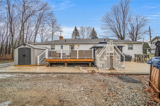 rear view of property featuring a wooden deck and a storage shed