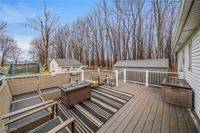 wooden deck featuring an outdoor living space with a fire pit, a trampoline, and a shed