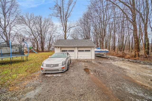 exterior space featuring a trampoline, a garage, an outbuilding, and a playground