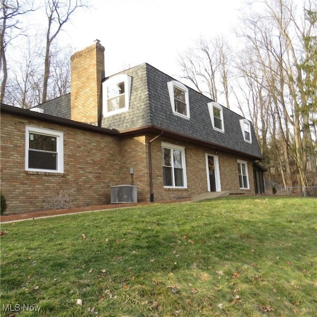 rear view of property featuring a yard and central AC unit