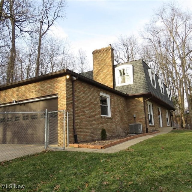 view of side of home with cooling unit, a garage, and a lawn