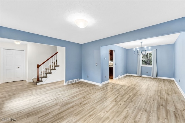 unfurnished living room with a notable chandelier and light hardwood / wood-style flooring