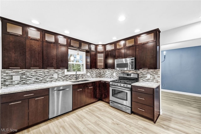 kitchen with sink, backsplash, stainless steel appliances, and light stone countertops