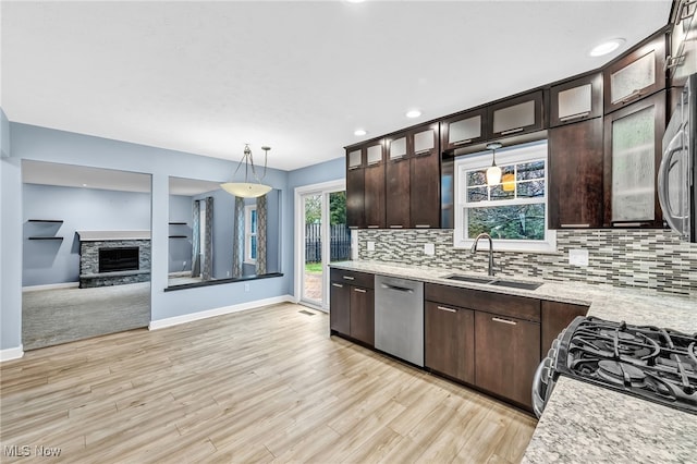 kitchen with sink, stainless steel appliances, tasteful backsplash, light stone countertops, and decorative light fixtures