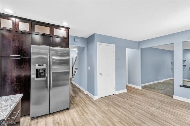 kitchen featuring dark brown cabinetry, light stone countertops, stainless steel fridge, and light hardwood / wood-style floors