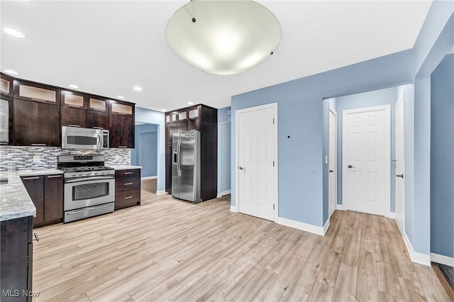 kitchen featuring dark brown cabinetry, stainless steel appliances, light hardwood / wood-style floors, and decorative backsplash