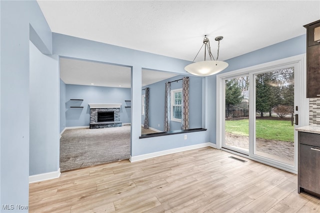 unfurnished dining area with a fireplace and light wood-type flooring