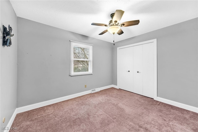 unfurnished bedroom with a closet, ceiling fan, and carpet flooring