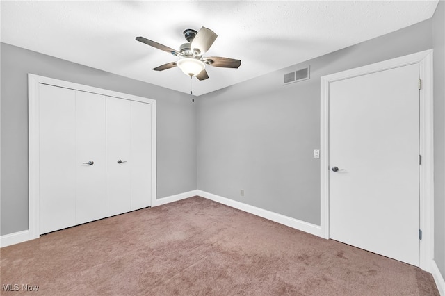 unfurnished bedroom with carpet, ceiling fan, and a closet