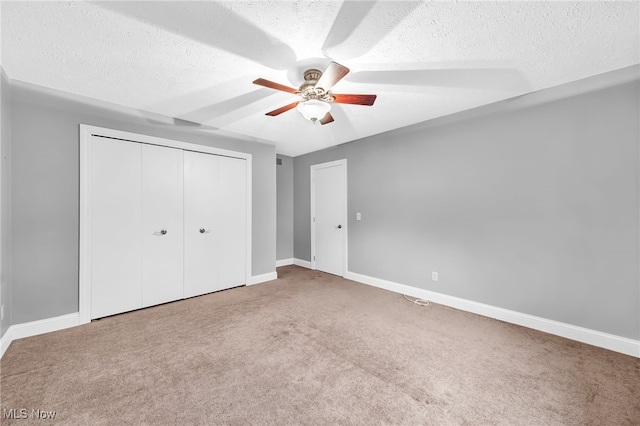 unfurnished bedroom with ceiling fan, carpet, a textured ceiling, and a closet