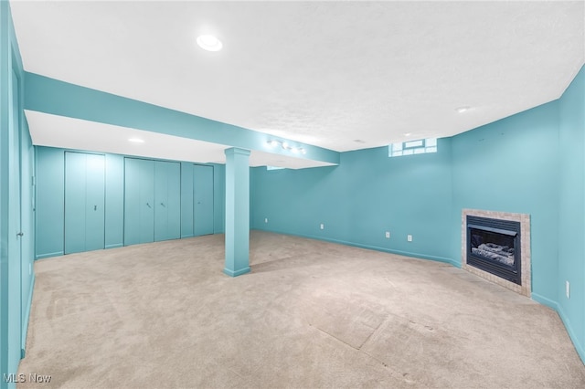 basement with light colored carpet and a fireplace