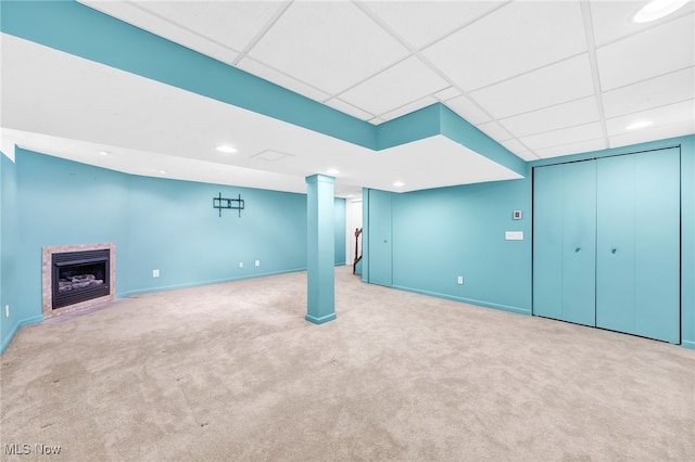 basement featuring a drop ceiling and light colored carpet