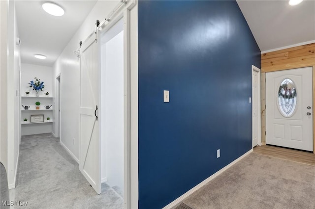 carpeted foyer entrance with a barn door and wood walls