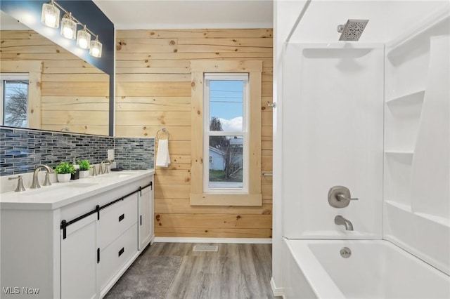 bathroom featuring shower / washtub combination, wooden walls, and a wealth of natural light