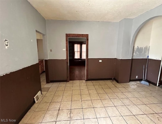 tiled empty room with a textured ceiling