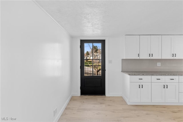 doorway with a textured ceiling and light wood-type flooring