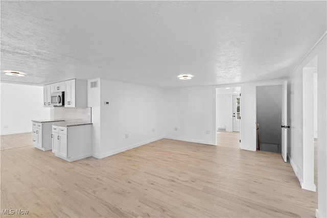 unfurnished living room featuring light hardwood / wood-style flooring and a textured ceiling