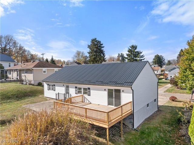 rear view of house featuring a wooden deck and a lawn