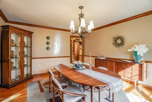 dining space with crown molding, a notable chandelier, and light hardwood / wood-style flooring