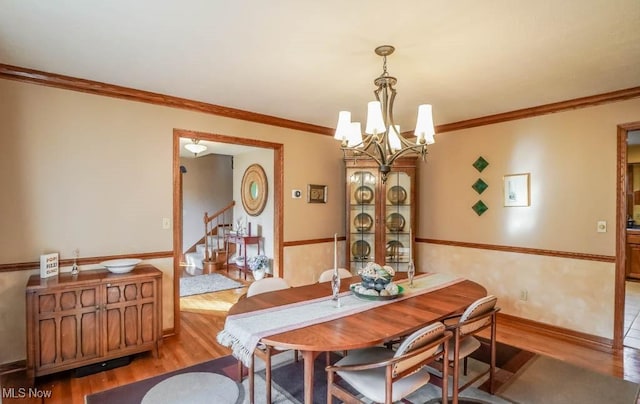 dining space with crown molding, a chandelier, and light wood-type flooring