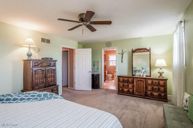 bedroom with ensuite bathroom, light carpet, and ceiling fan