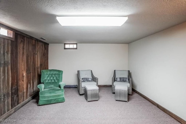 sitting room with a textured ceiling, carpet, and wood walls