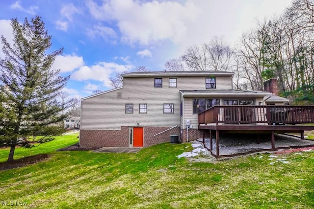 rear view of property featuring a wooden deck and a lawn