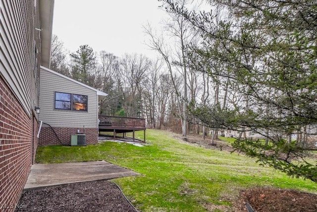 view of yard featuring central AC, a deck, and a patio area