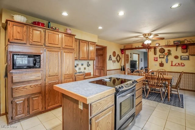 kitchen featuring electric stove, ceiling fan, a kitchen island, black microwave, and light tile patterned flooring