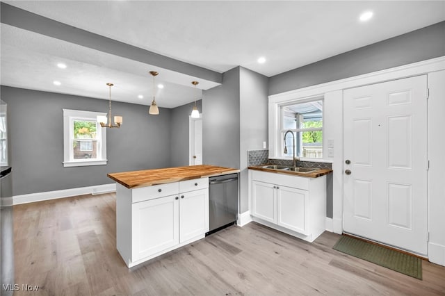 kitchen featuring butcher block countertops, sink, white cabinetry, hanging light fixtures, and stainless steel dishwasher