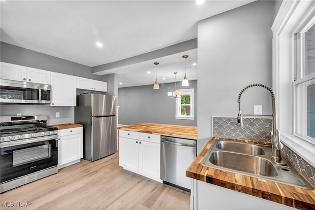 kitchen with stainless steel appliances, sink, white cabinets, and wooden counters