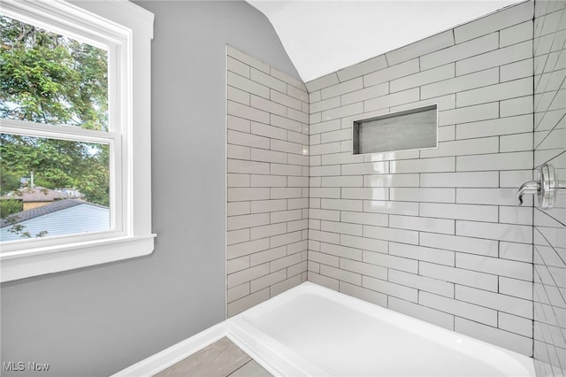 bathroom featuring vaulted ceiling and tiled shower