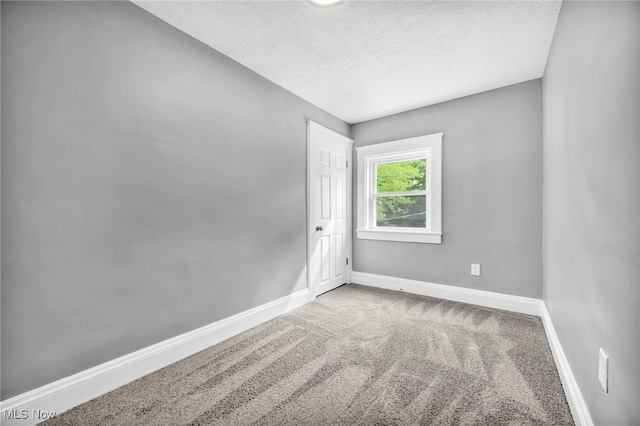 carpeted empty room featuring a textured ceiling