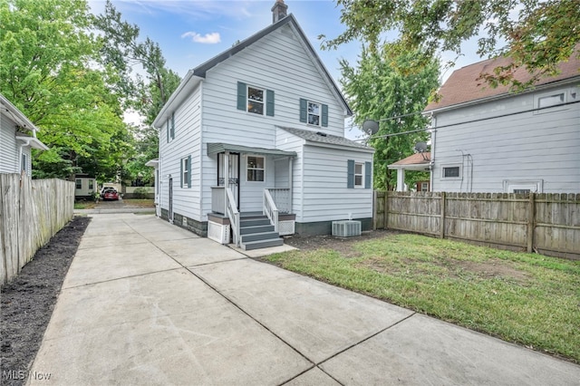 back of property with central AC and a lawn