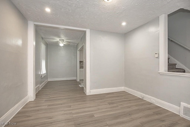 empty room with hardwood / wood-style flooring, ceiling fan, and a textured ceiling