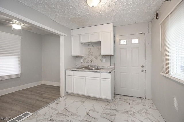 kitchen featuring white cabinetry, sink, decorative backsplash, and a textured ceiling