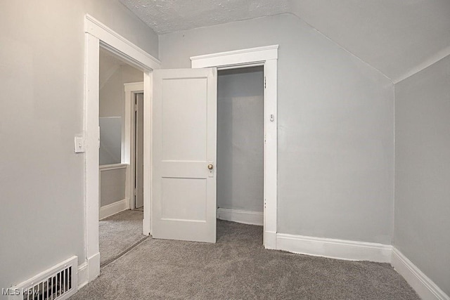 interior space featuring lofted ceiling, carpet floors, and a textured ceiling