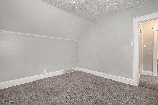 bonus room with lofted ceiling, carpet flooring, and a textured ceiling