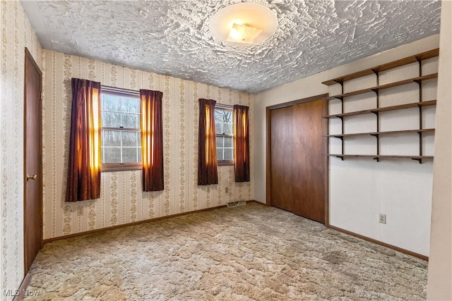 carpeted empty room with a textured ceiling