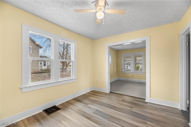 spare room featuring hardwood / wood-style flooring, ceiling fan, and a textured ceiling