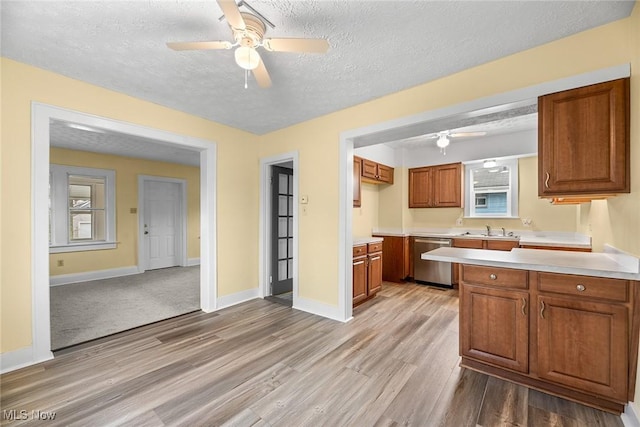 kitchen featuring dishwasher, sink, ceiling fan, light hardwood / wood-style floors, and a textured ceiling