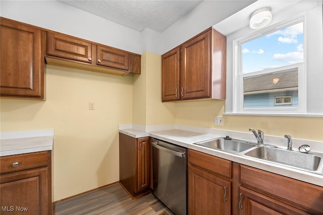 kitchen with dishwasher, sink, a textured ceiling, and light hardwood / wood-style flooring