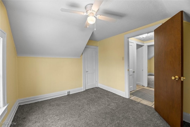 bonus room featuring lofted ceiling, a textured ceiling, light colored carpet, and ceiling fan