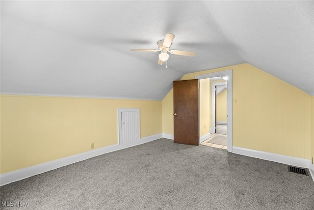 additional living space with ceiling fan, lofted ceiling, carpet floors, and a textured ceiling