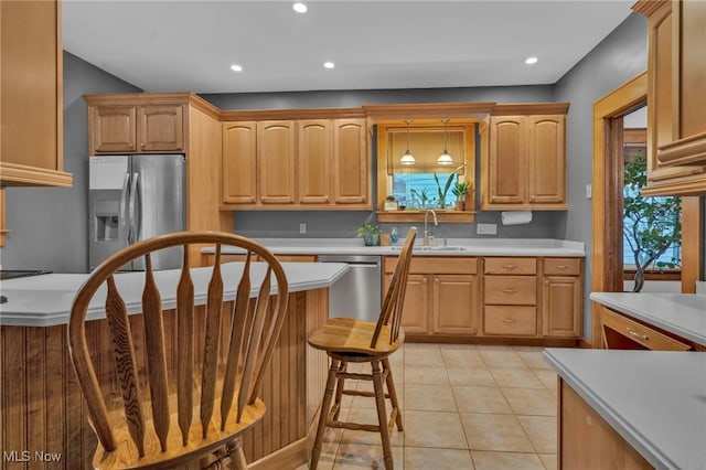 kitchen with appliances with stainless steel finishes, sink, hanging light fixtures, and light tile patterned floors