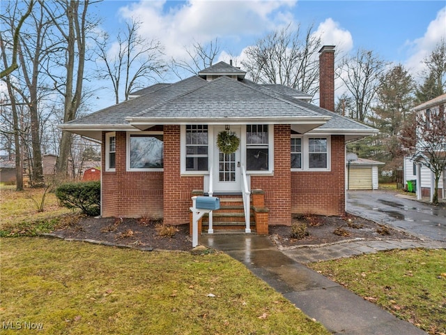 bungalow-style house with a garage, an outdoor structure, and a front yard